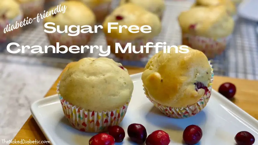 picture of 2 sugar free cranberry muffins on a plate with cranberruies on the table and muffins in the background